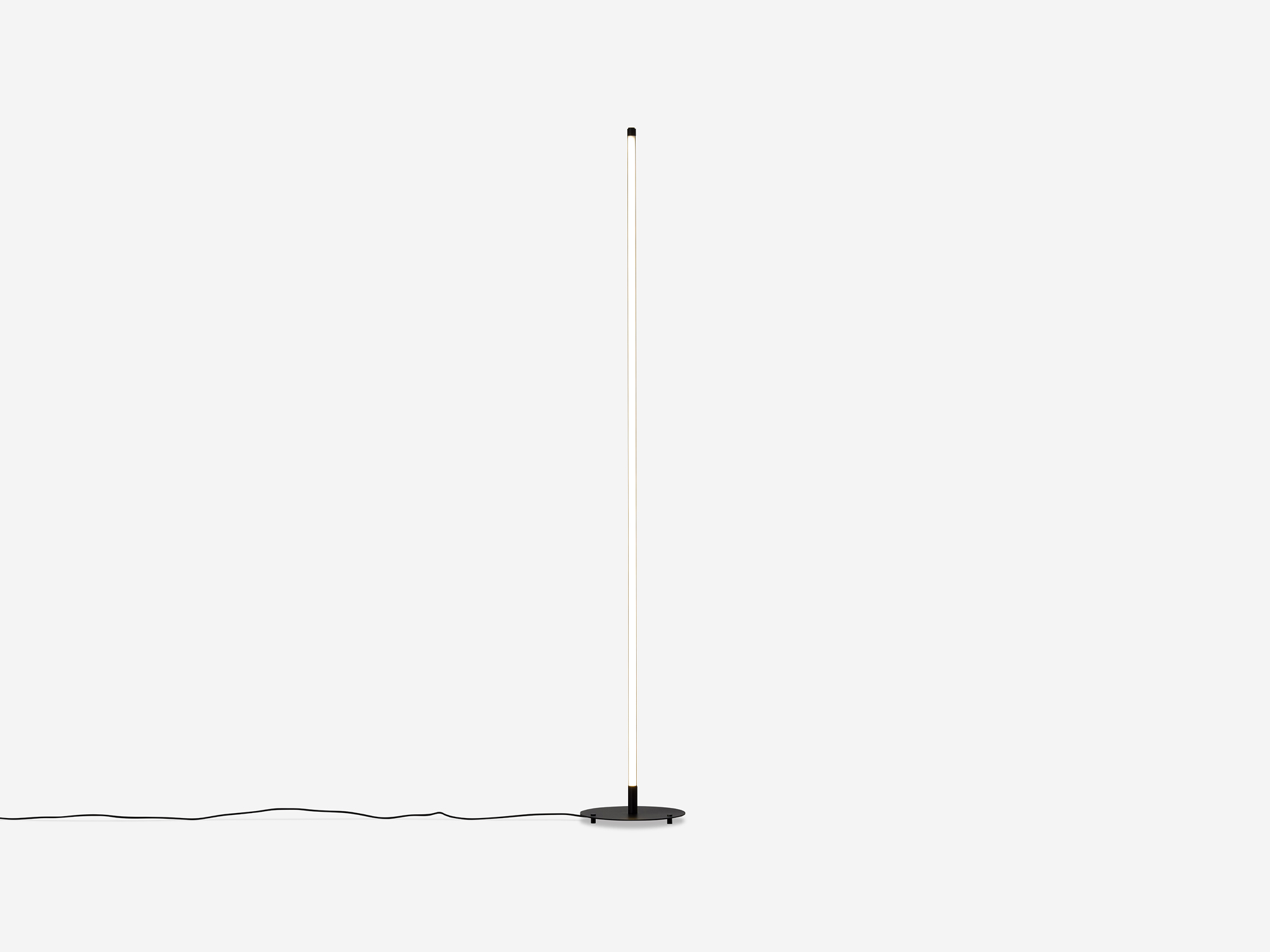 Thin black floor lamp with light on